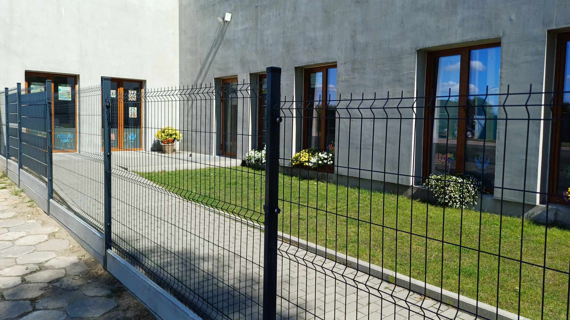 Budynek Bajkowej Krainy, teren zielony oraz aktualne ogrodzenie panelowe z furtką
